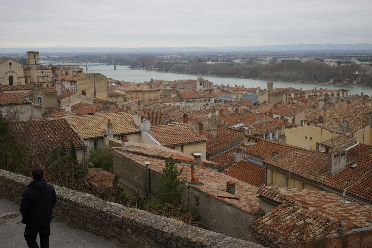 Nappe de toits de tuile à faible pente vue depuis une colline, cheminées, fleuve au fond